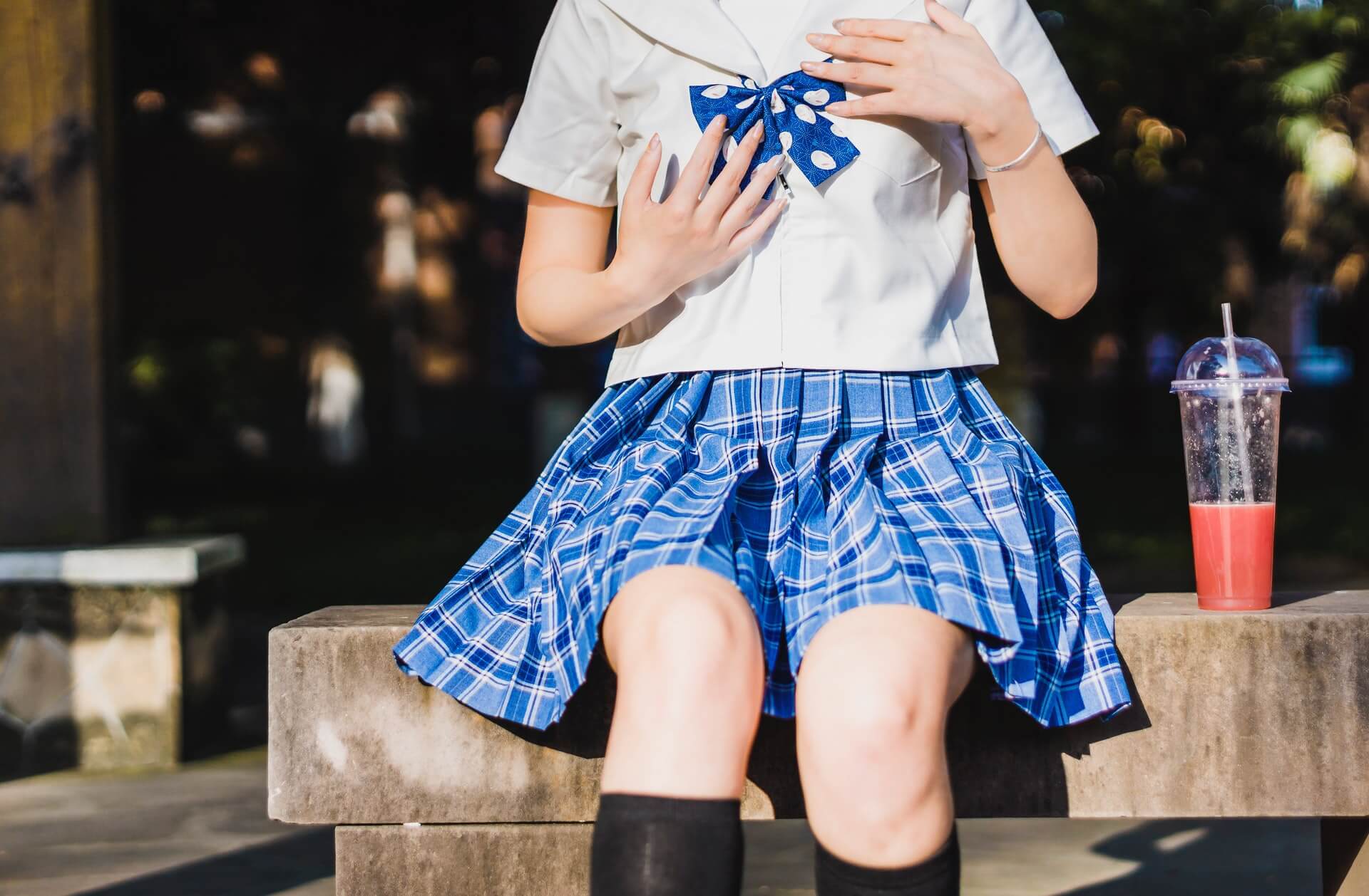 siedząca dziewczynka, która ma na sobie mundurek szkolny