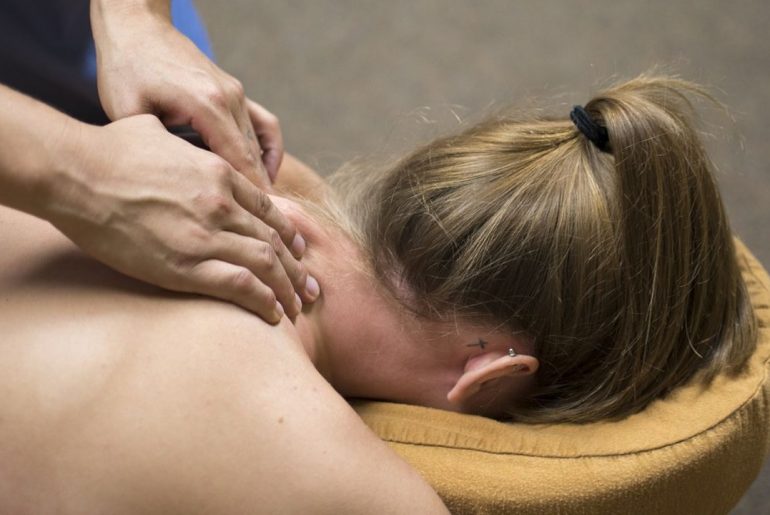 Dłonie osoby masującej kobietę