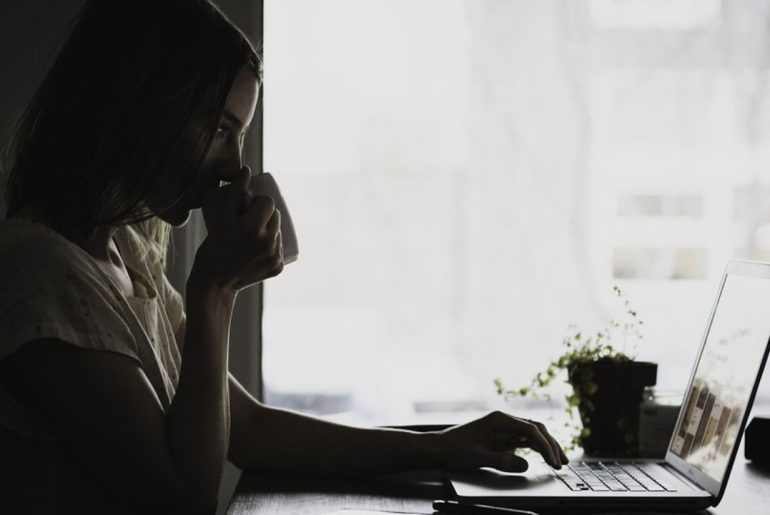 Kobieta pijąca kawę przy laptopie