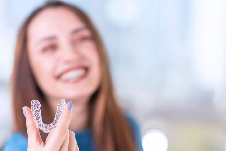 Praca w gabinecie ortodontycznym - kobieta trzymająca nakładkę na zęby
