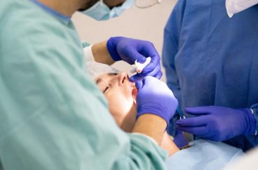 Dentysta i asystentka podczas zabiegu na pacjencie