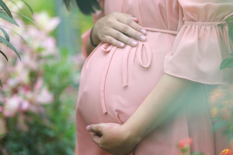 Kobieta trzymająca się za brzuch ciążowy